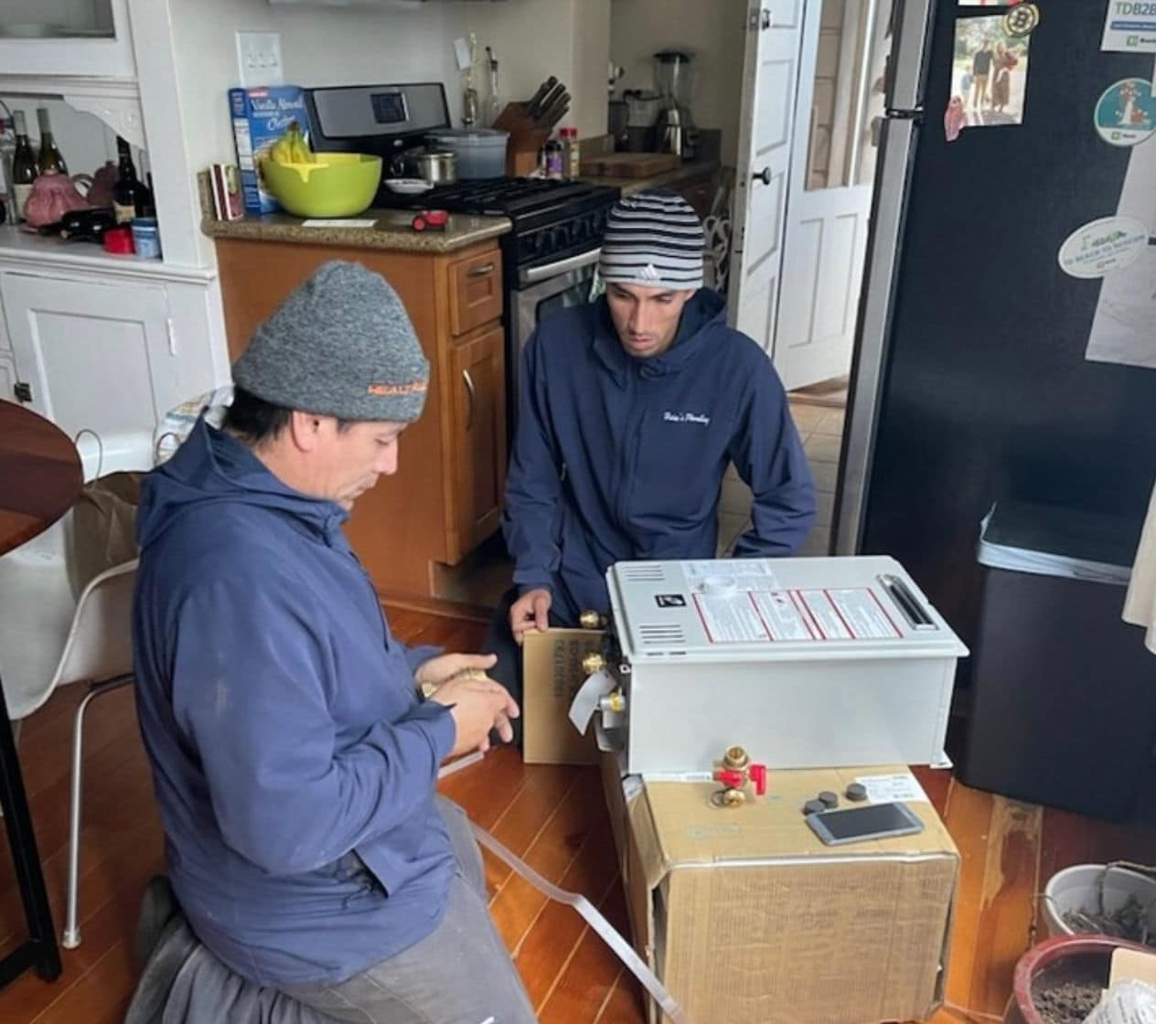 Heise's Plumbing crew preparing a new tankless water heater unit for installation